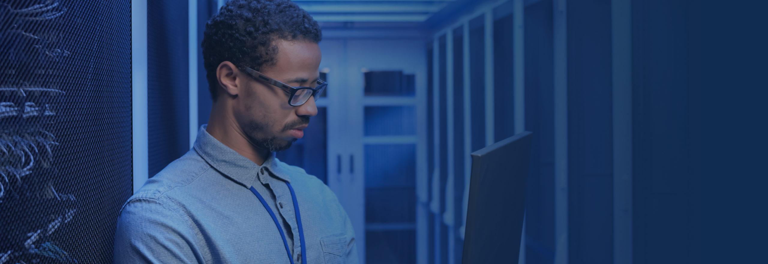 man on laptop in data center providing HPE server management & maintenance